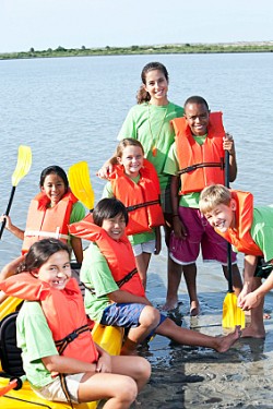 Summer camp counselor and children with kayak