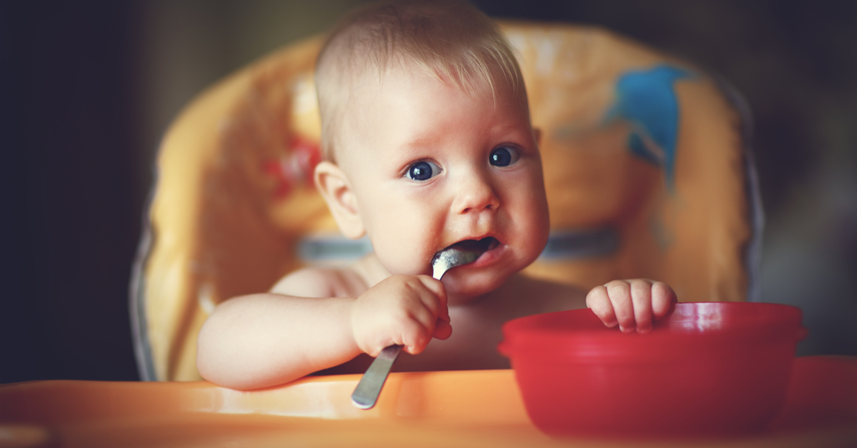 baby eating out of red bowl