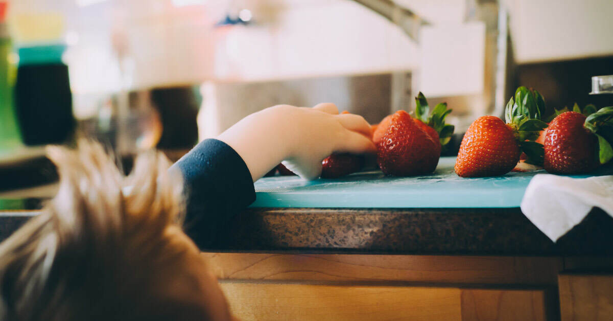 kid reaching for strawberries