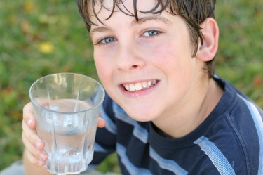 shot of a boy drinking a glass of water smile