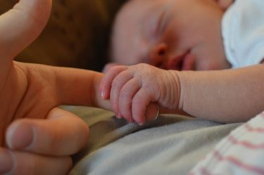 newborn baby holds finger