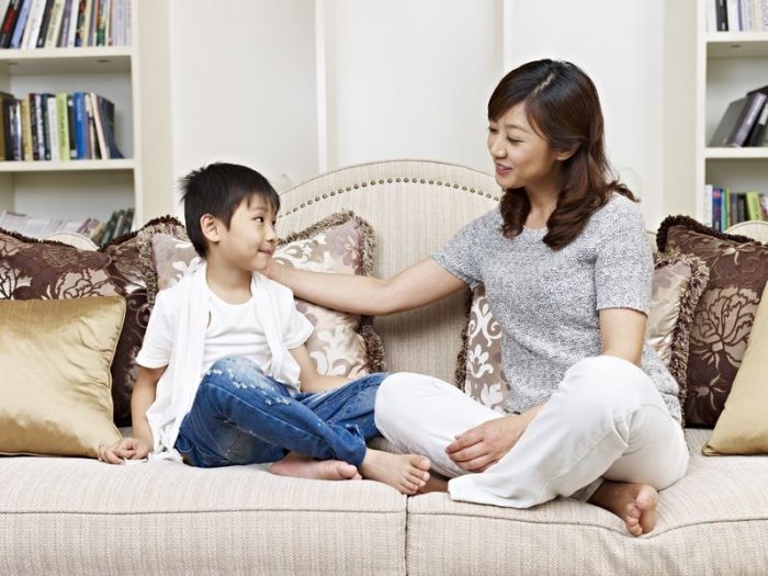 mother, son, Asian, couch, pillows, beige, white, gray, blue, books, living room, talk, talking, conversation
