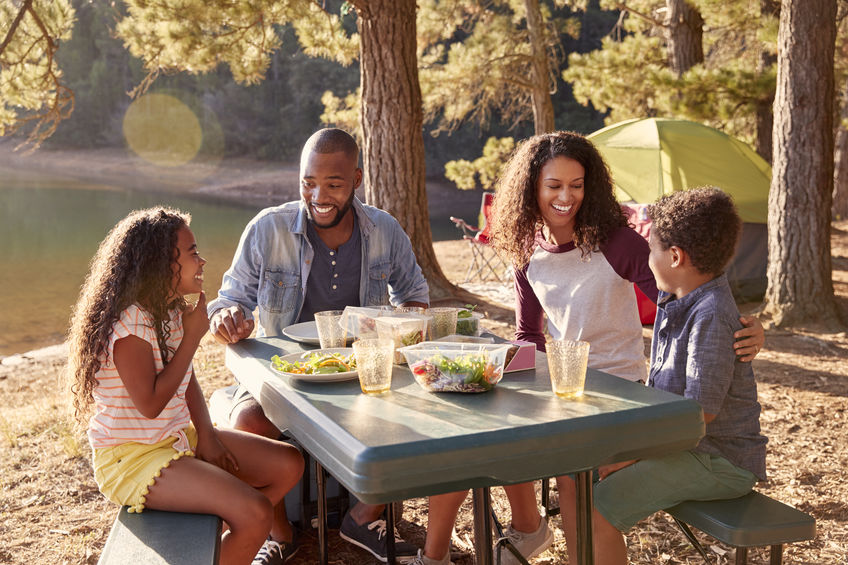 mother, father, daughter, son, outdoors, grass, trees, table, food, drinks, water, yellow, green, blue