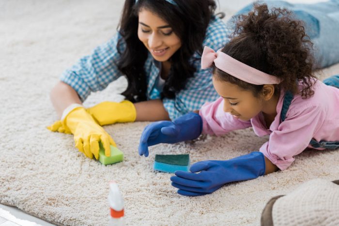 woman and young girl scrubbing carpet