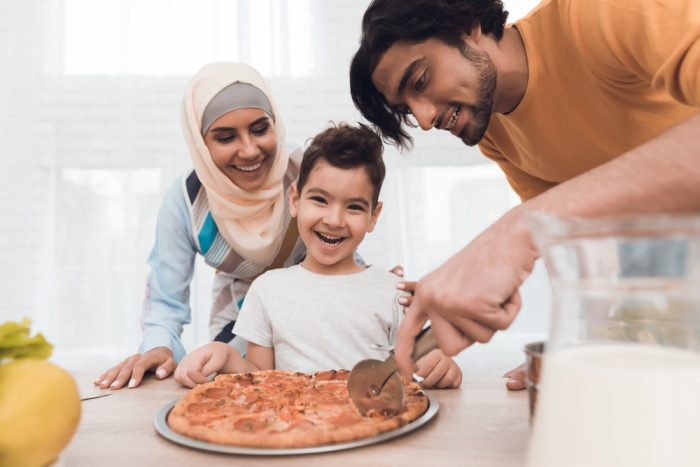 middle eastern family cutting a pizza