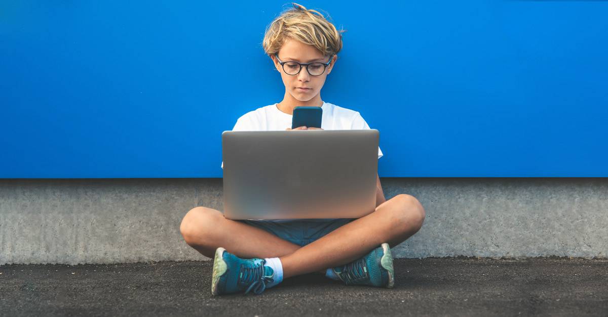 boy using laptop and iphone