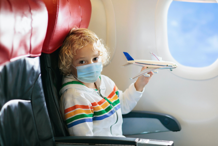 boy in airplane seat with mask