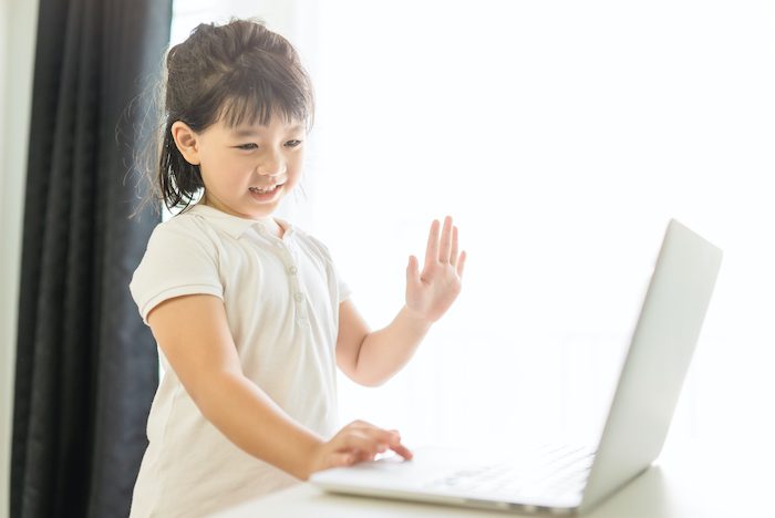 child waving at laptop