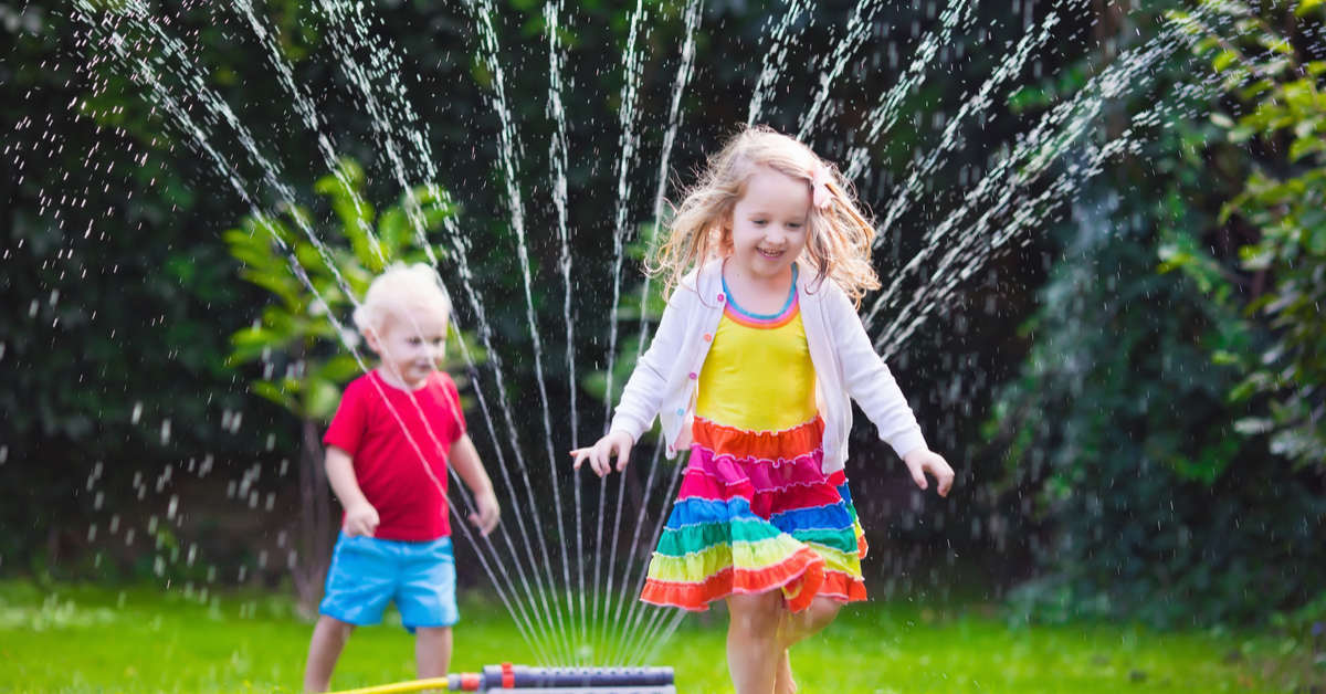kids playing in sprinkler in yard