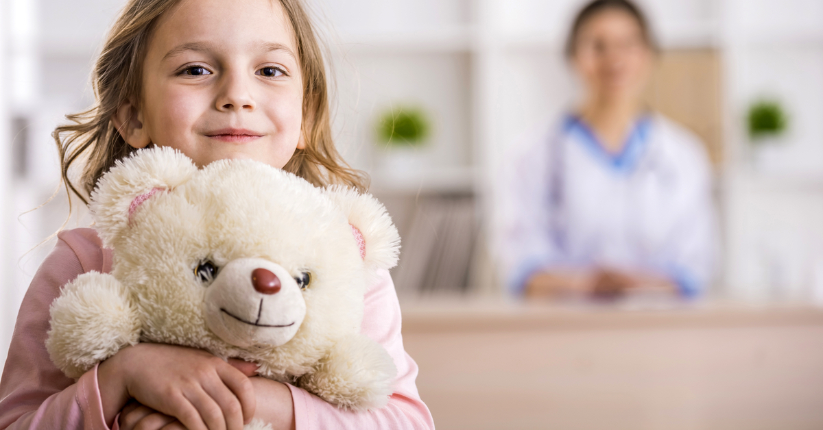girl holding teddy bear in hospital 