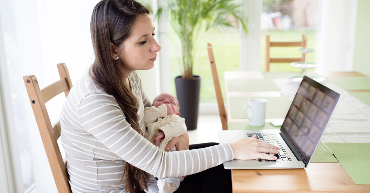mother holding infant and using laptop