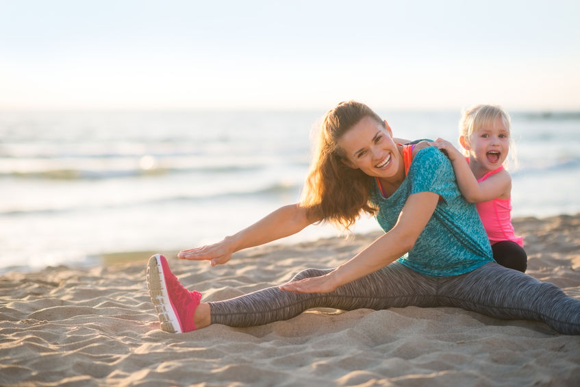 parent and child exercising at the beach